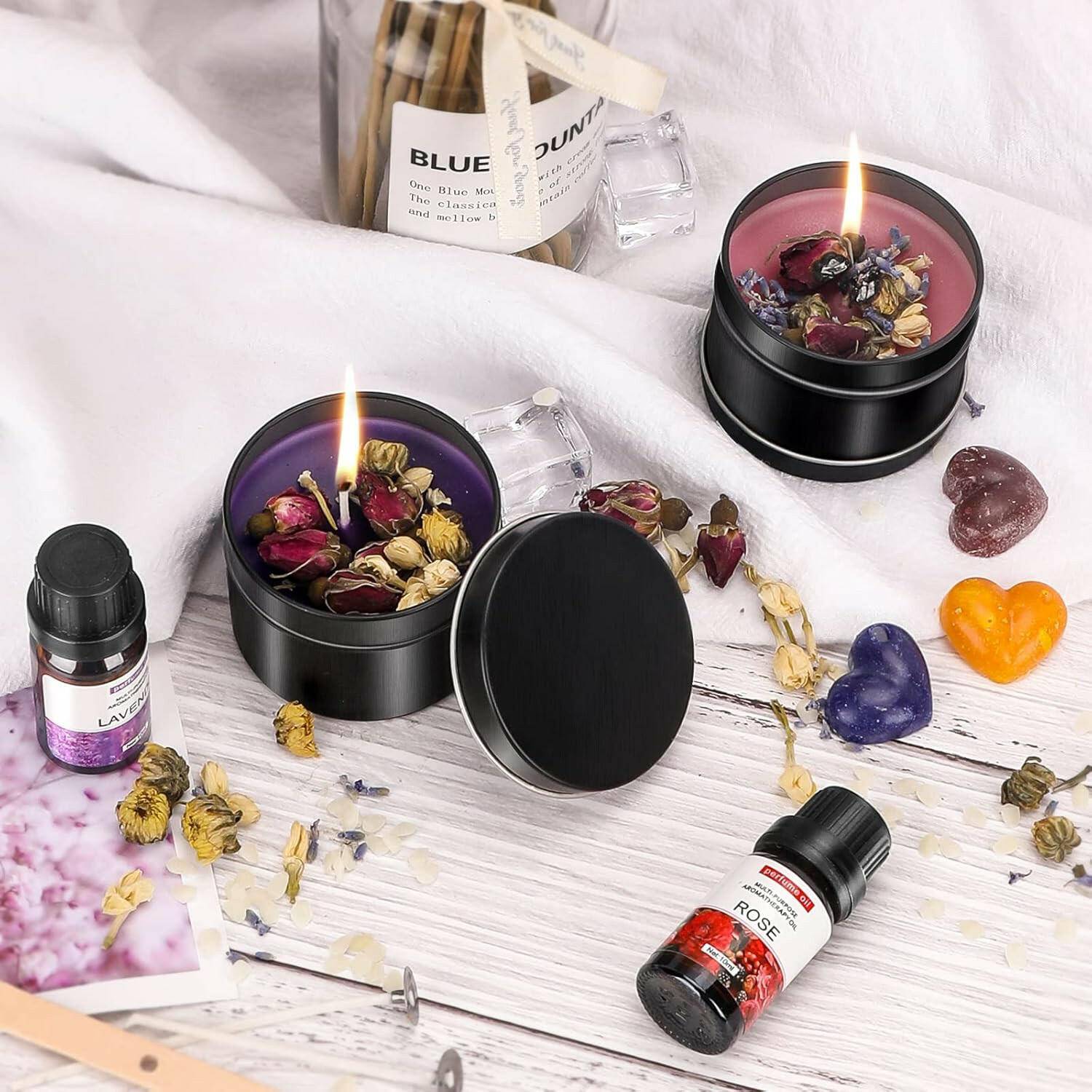 Creative Candle Making Kit featuring soy wax candles in black tins, essential oils, dried flowers, and crafting tools on a white surface.