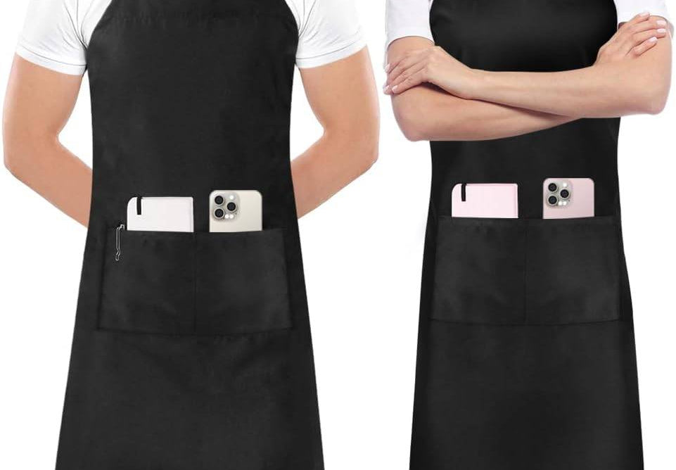 Chef's Choice Kitchen Aprons in black with adjustable straps, front pockets holding phones, modeled by a man and a woman.